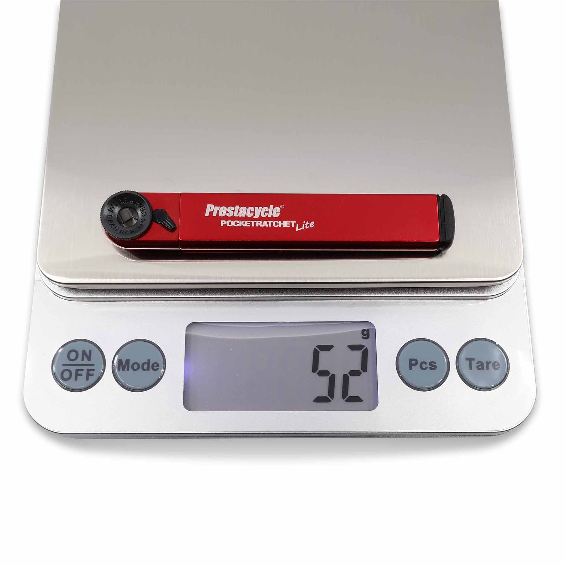 A Prestacycle PocketRatchet Lite multi-tool with bits stored in the handle sits on a digital kitchen scale, showing a weight of 52 grams.